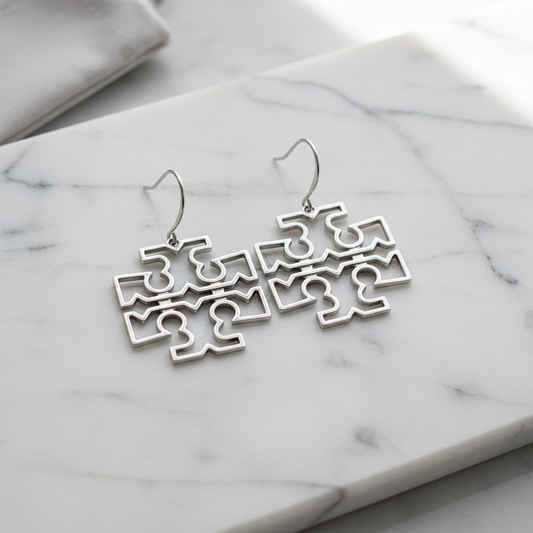 Tory Burch Britten silver drop earrings flat lay on white marble