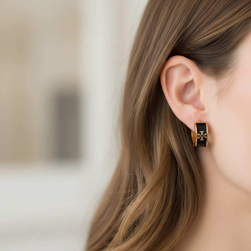 Tory Burch black enamel huggie earrings worn on ear