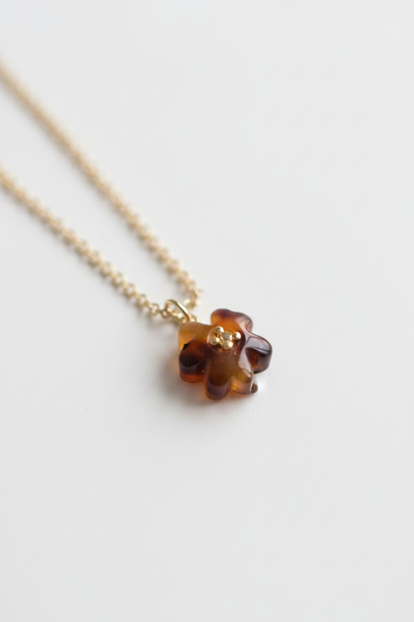 Close-up macro of Tory Burch tortoiseshell resin flower pendant