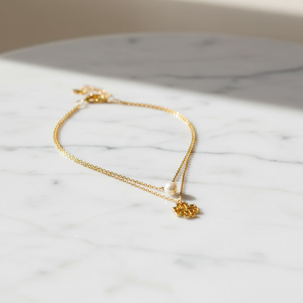 Tory Burch Britten Layered Necklace on marble surface, editorial lifestyle shot