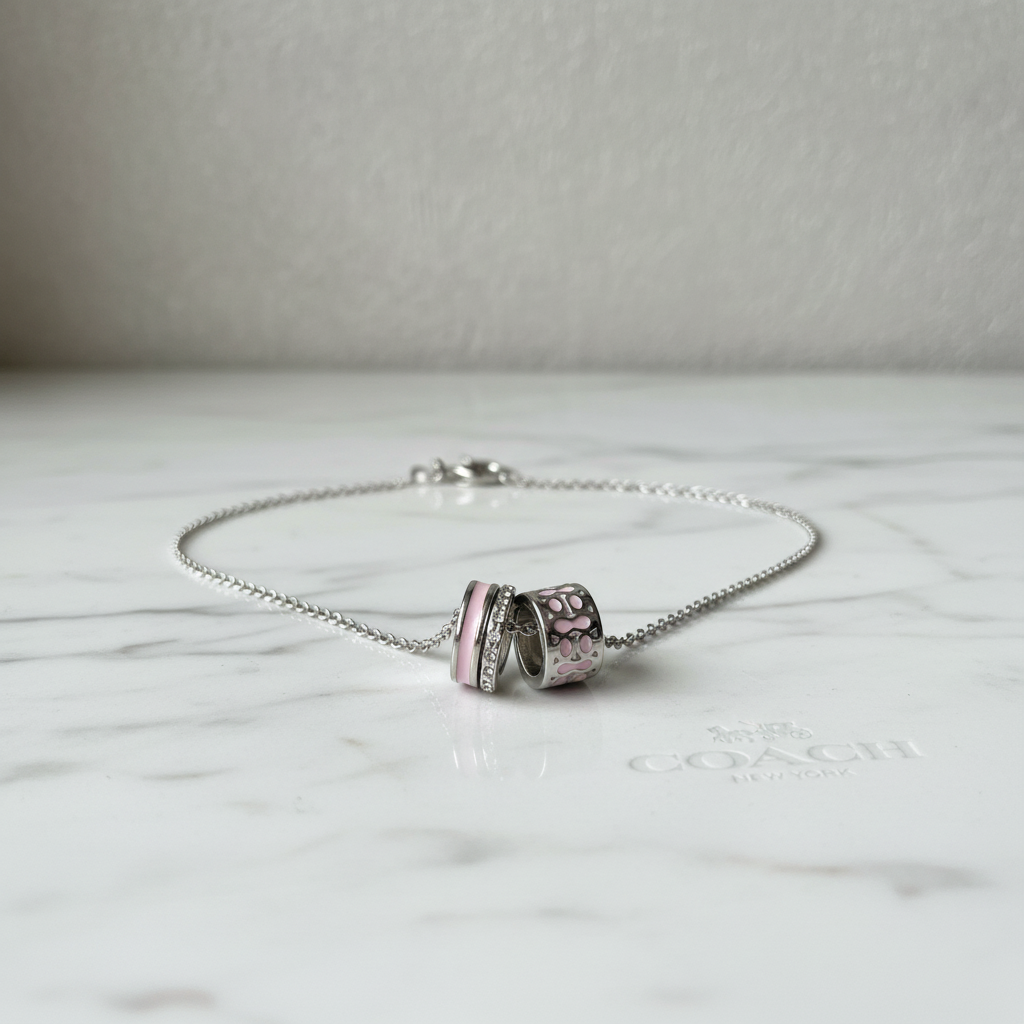 Coach Pink Signature Enamel Necklace on marble surface, editorial lifestyle shot