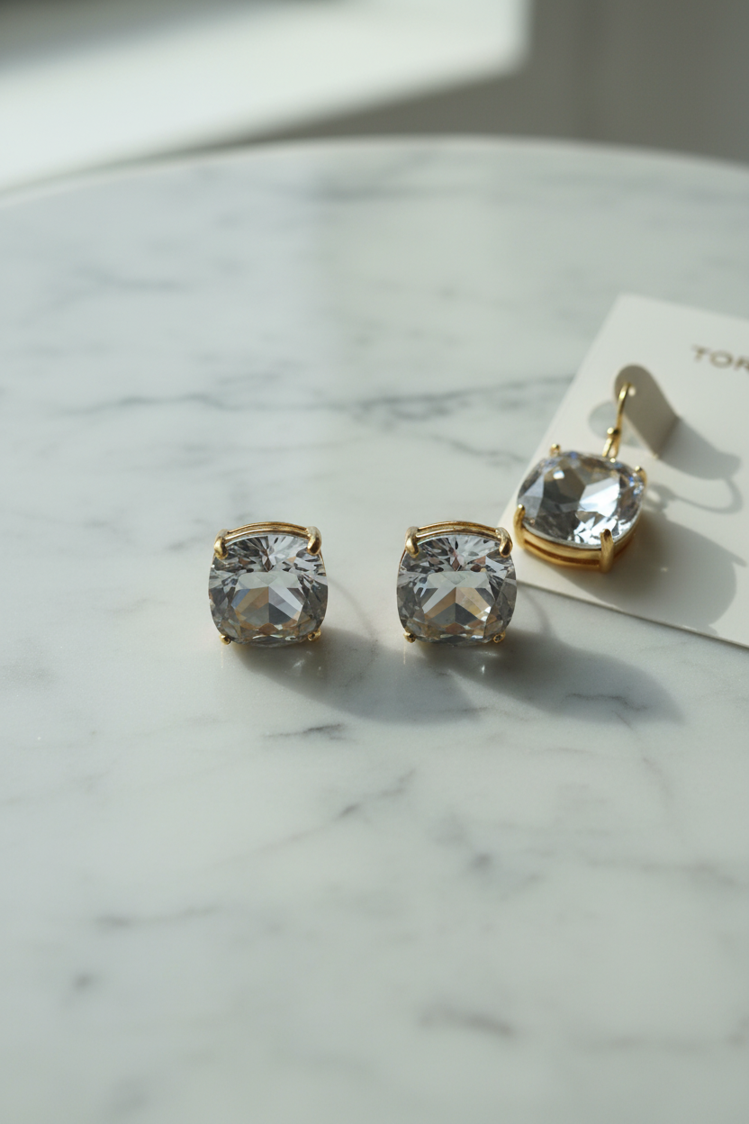 Tory Burch crystal cushion cut drop earrings flat lay on white marble