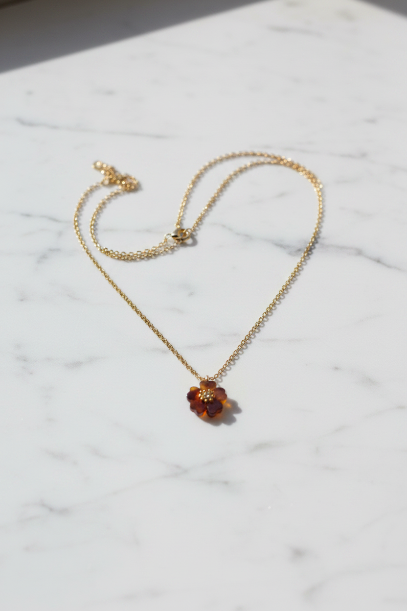 Tory Burch tortoiseshell resin flower pendant necklace flat lay on white marble